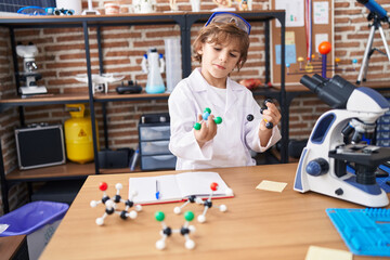 Adorable caucasian boy student holding molecules at classroom