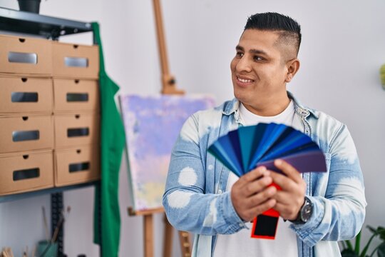 Young latin man artist smiling confident holding test color at art studio