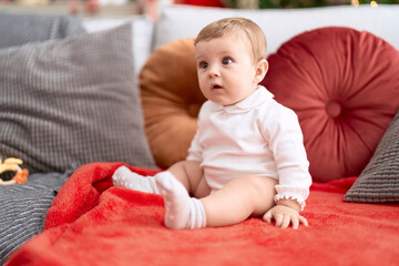 Fototapeta premium Adorable toddler sitting on sofa with relaxed expression at home