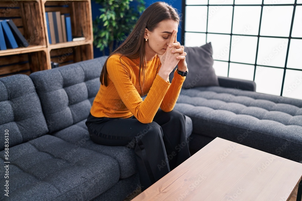 Poster Young caucasian woman stressed sitting on sofa at home