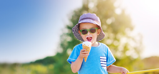 Cute boy eating ice cream in sunny day in nature.