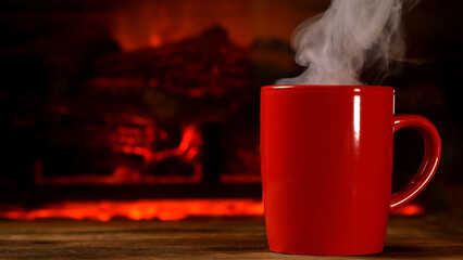 Steaming cup of hot beverage coffee or tea on wooden board by burning fireplace. - 568838512