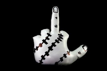 White sculpture in shape of hand showing obscene gesture against black background.