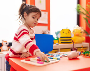 Fototapeta premium Adorable hispanic girl playing with maths puzzle game standing at kindergarten