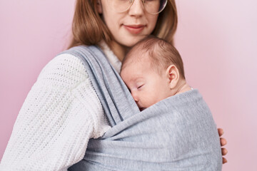 Mother and son hugging each other standing over isolated pink background
