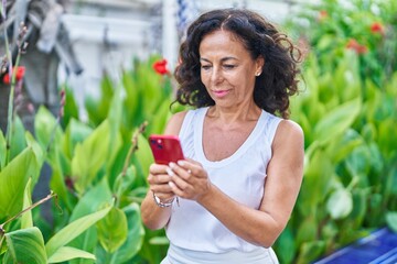 Middle age woman using smartphone with serious expression at park
