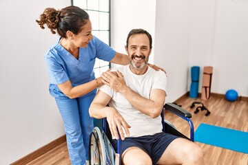 Fototapeta premium Middle age man and woman smiling confident having physiotherapy session at physiotherapy clinic