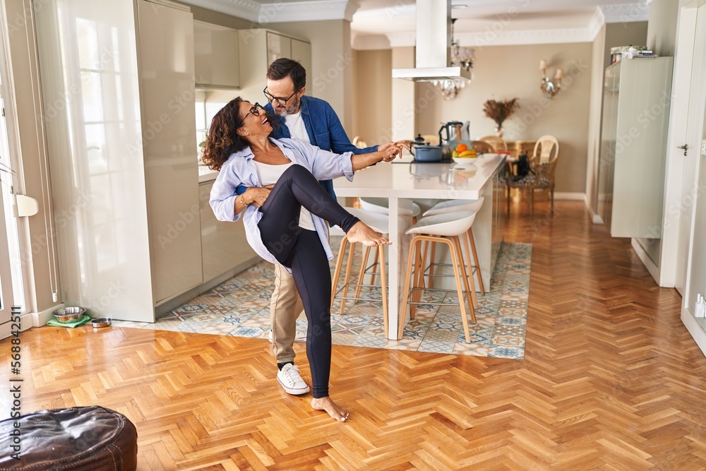 Wall mural Middle age hispanic couple smiling confident dancing at home