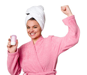 A woman, dressed in a cozy pink bathrobe and a towel on her head, holds a deodorant with a big...