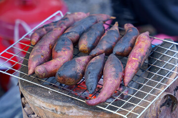 The pink sweet potato is roasting on the grill on the stove.