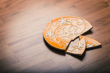 Broken ceramic plate on wooden floor