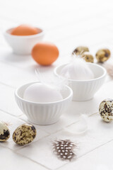 Different eggs with feathers for Easter on white background