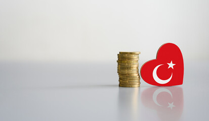A stack of coins and the flag of Turkey in the shape of a heart. The concept of donations and...