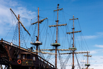 Sailing ship mast with rigging and cables against the sky.