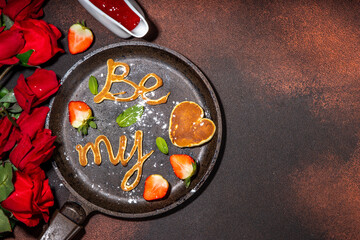 Cute Valentine pancakes, sweet homemade butter cake shaped in form of I love you, Be my heart inscription. Breakfast or gift idea for Saint Valentine day, with strawberry and syrup. roses bouquet