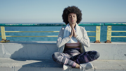 African american woman wearing sportswear doing yoga exercise at seaside