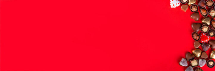 Valentines Day chocolates banner, background, frame. Various sweets and chocolate candy on red paper background with copy space. Romantic composition. Happy Valentine's day greeting card background