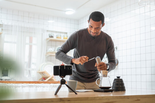 Black African American male making coffee drip in kitchen, Hot drink, Barista at home, Video call on mobile phone or smartphone.