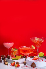 Valentine day romantic bar background. Set various red, pink, chocolate alcohol drinks for Valentine day party or dating, in different cocktail glasses with strawberry, heart decor, chocolates