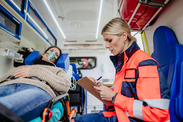 Rescuer taking care of patient, writing her diagnosis. © Halfpoint