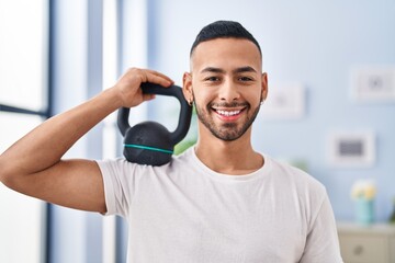 African american man smiling confident holding kettlebell at home