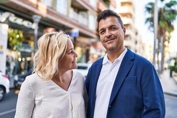 Middle age man and woman couple hugging each other standing at street