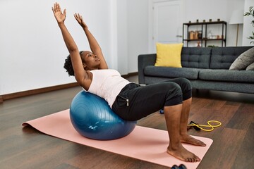 African american woman training abs exercise using fit ball at home