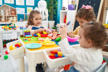 Group of kids playing with construction blocks sitting on table at kindergarten