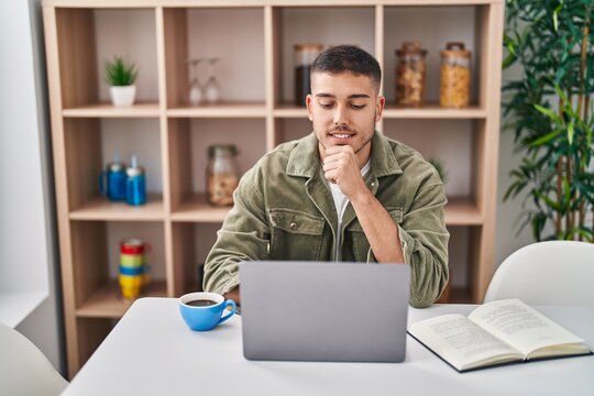 Young Hispanic Man Sitting On Table Studying At Home