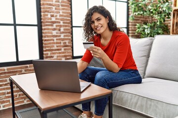 Young latin woman using credit card and laptop at home