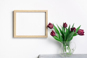 Horizontal blank picture frame mockup on white wall with red tulips flowers