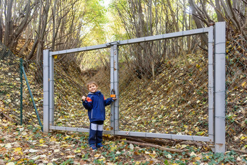 Illegal gate on Fruska Gora mountain in Serbia. The boy is standing by the gate in forest