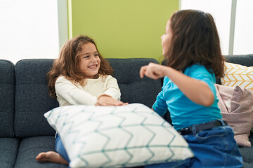 Two kids smiling confident sitting on sofa speaking at home