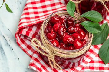 Jar of cherry jam and sour cherries. Berries cherry with syrup. Ripe ripe Sweet red cherries. Canned fruit on a light background