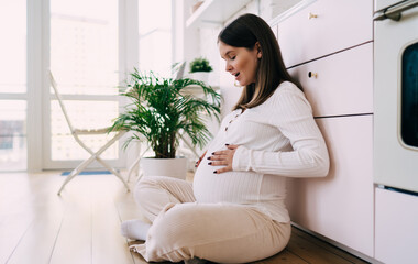 Young childbearing woman sitting on floor and enjoying time at home