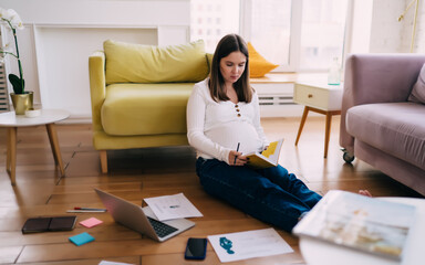 Pregnant woman working on project while sitting on floor