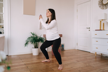 Pregnant woman squatting during fitness training at home