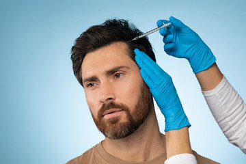 Mesotherapy for hair. Middle aged man getting injections in head, having mesotherapy session, blue background