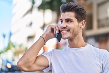 Young hispanic man smiling confident talking on the smartphone at street