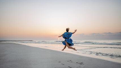 Fototapeta na wymiar Young woman enjoying time at sea, jumping.