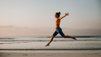 Fototapeta na wymiar Young excited woman running and jumping at beach, morning routine and healthy lifestyle concept.