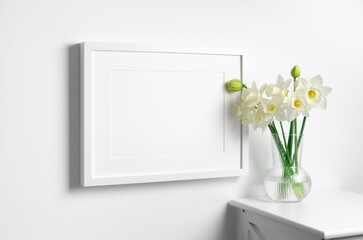 Blank landscape picture frame mockup in white interior with spring flowers