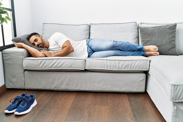 Young hispanic man lying on sofa sleeping at home