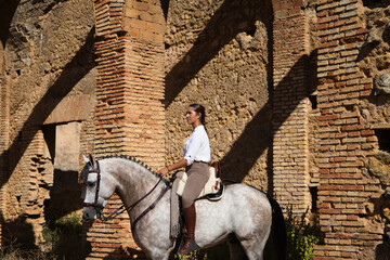 Young and beautiful Spanish woman on a Thoroughbred horse for competition. The woman has gone out...