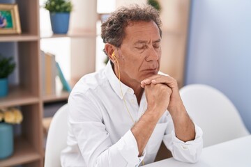 Naklejka premium Middle age man listening to music sitting on table at home