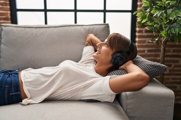 Young beautiful hispanic woman listening to music relaxed on sofa at home