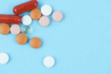 Assorted pharmaceutical medicine pills, tablets and capsules over blue background