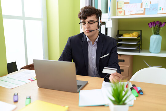 Non binary man call center agent using computer and credit card working at office