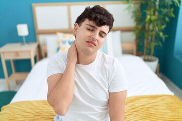 Non binary man suffering for cervical injury sitting on bed at bedroom
