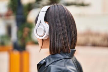 Young beautiful hispanic woman listening to music at park